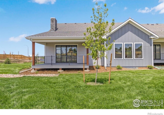 back of house with covered porch and a lawn