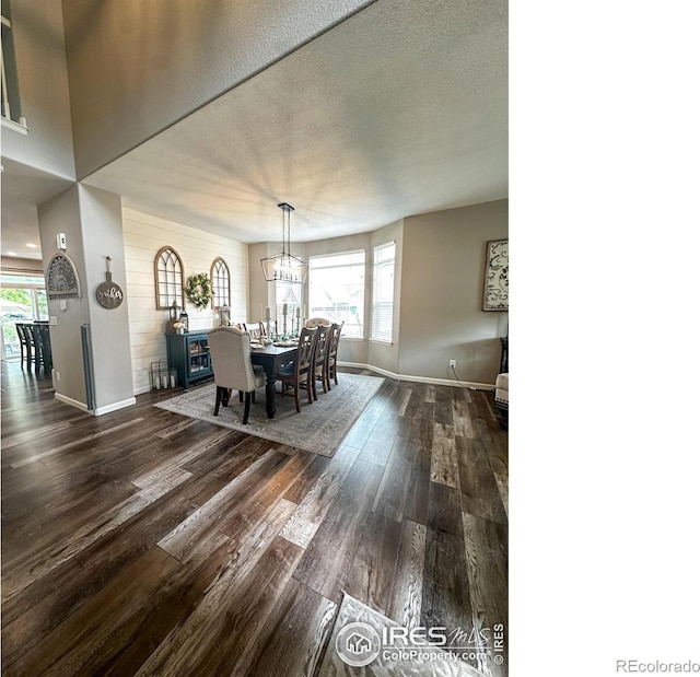 dining area with a wealth of natural light, dark wood-type flooring, a textured ceiling, and an inviting chandelier