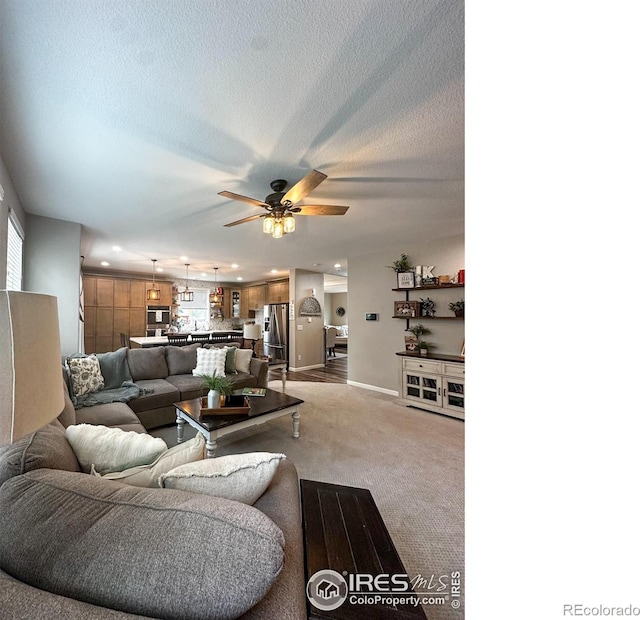 living room featuring ceiling fan, a textured ceiling, and light carpet