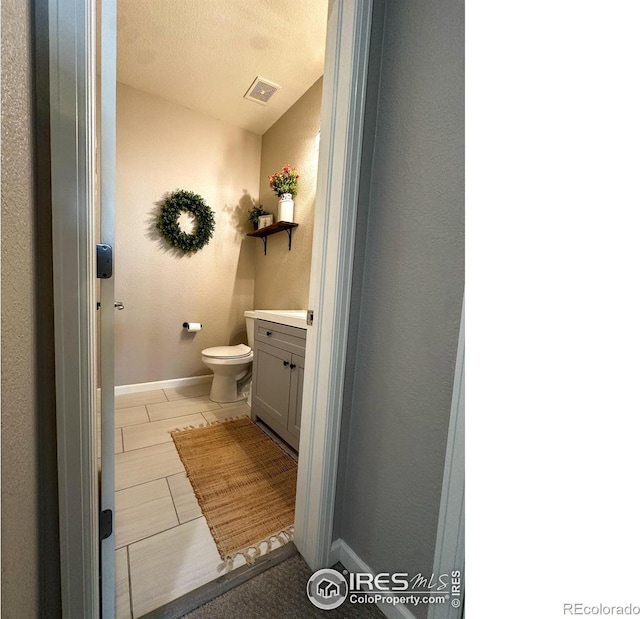 bathroom featuring toilet, vanity, and a textured ceiling