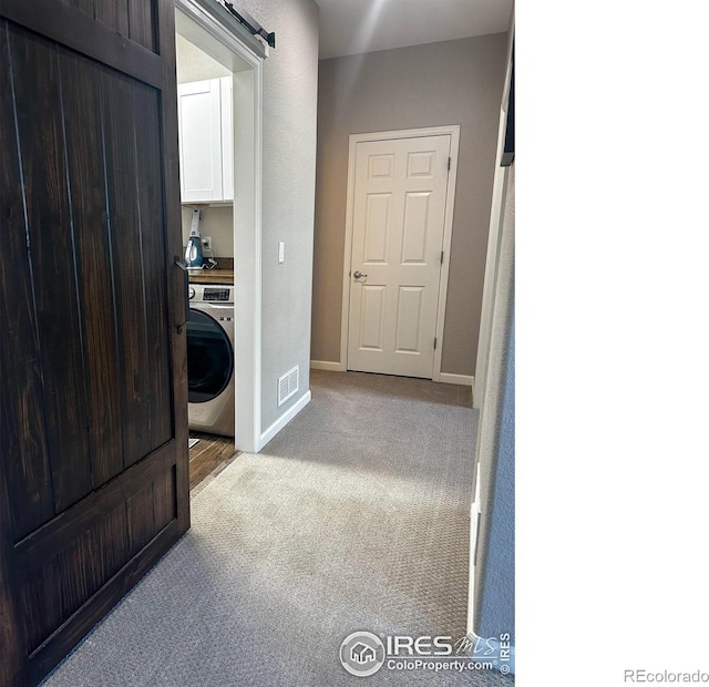 corridor featuring washer / clothes dryer and light colored carpet