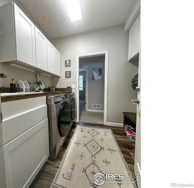 clothes washing area with cabinets, dark hardwood / wood-style floors, and independent washer and dryer