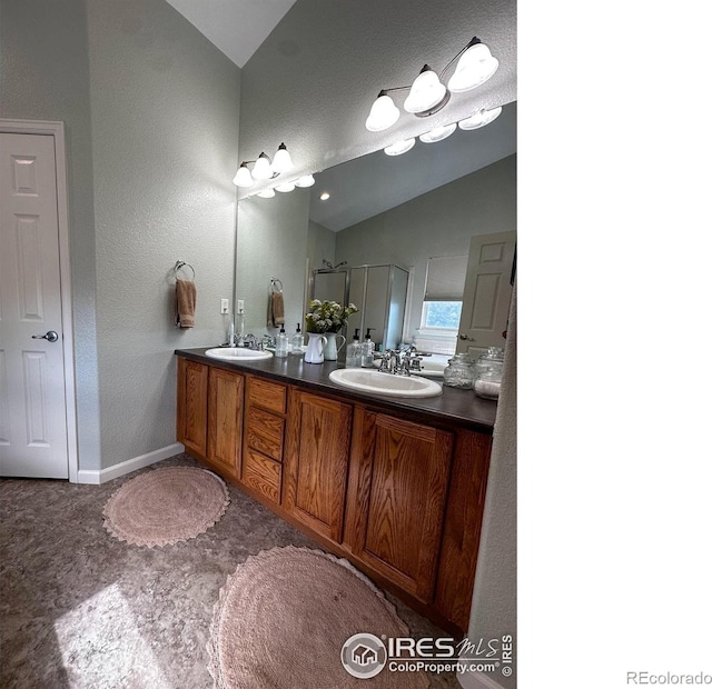 bathroom with a shower with door, vanity, and vaulted ceiling