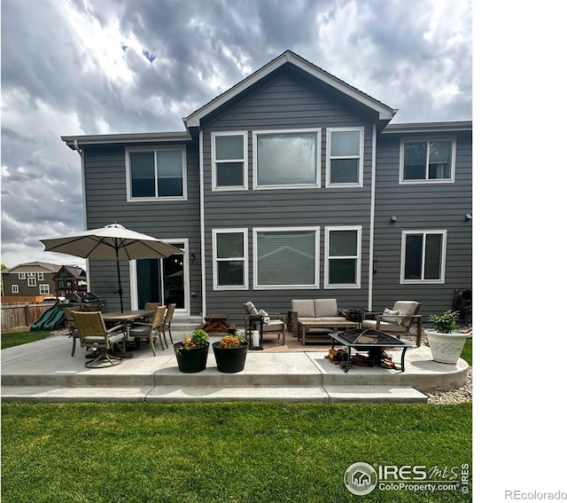 back of house with an outdoor living space with a fire pit, a patio area, and a lawn