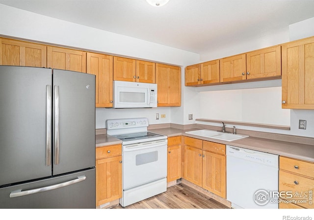 kitchen with white appliances, sink, and light hardwood / wood-style floors