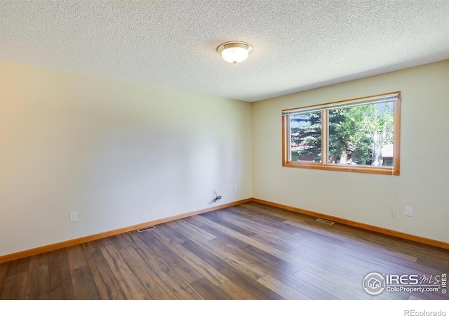 spare room featuring hardwood / wood-style floors and a textured ceiling