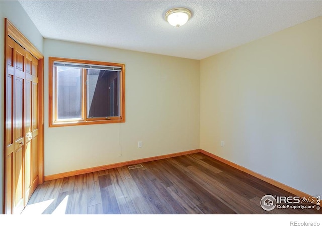 unfurnished room featuring wood-type flooring and a textured ceiling