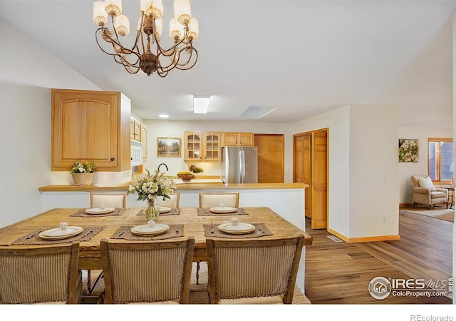 dining area with hardwood / wood-style floors and an inviting chandelier