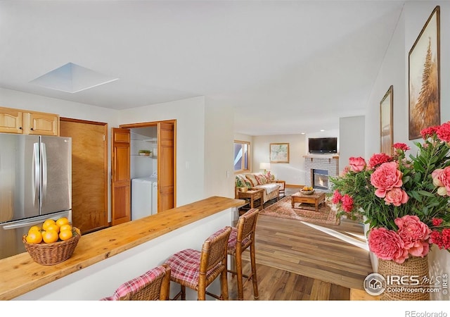 dining room featuring a brick fireplace, washer / dryer, and wood-type flooring