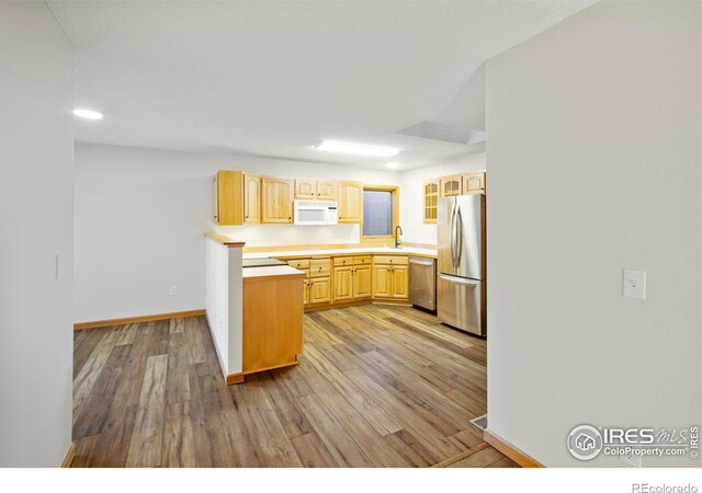 kitchen featuring light brown cabinetry, sink, light hardwood / wood-style flooring, and appliances with stainless steel finishes