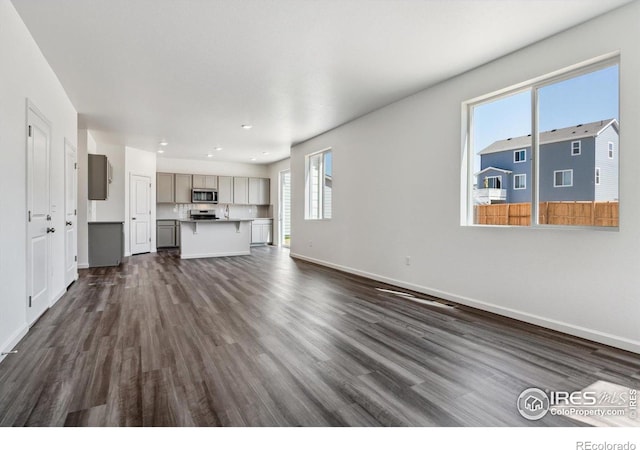 unfurnished living room featuring dark wood-type flooring, a wealth of natural light, and sink