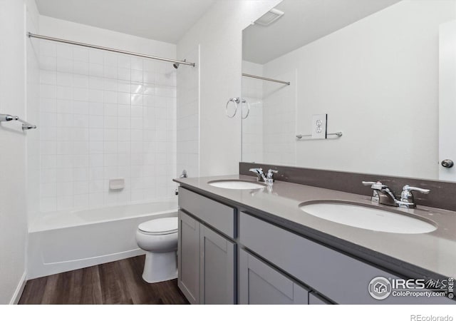 full bathroom featuring hardwood / wood-style flooring, vanity, toilet, and tiled shower / bath combo