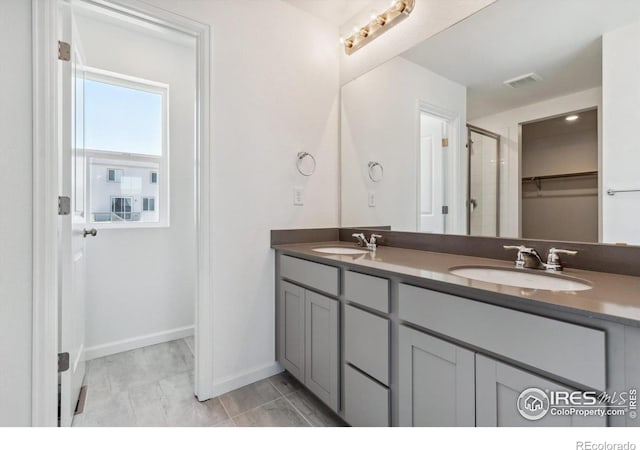 bathroom with an enclosed shower, vanity, and tile patterned floors