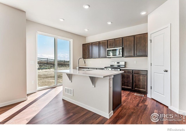 kitchen with a center island with sink, appliances with stainless steel finishes, sink, and dark hardwood / wood-style floors