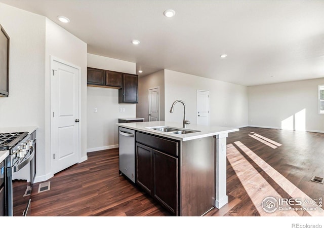 kitchen with stainless steel appliances, a kitchen island with sink, sink, and dark wood-type flooring