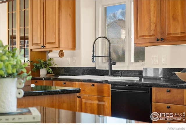 kitchen featuring sink, black dishwasher, and dark stone countertops