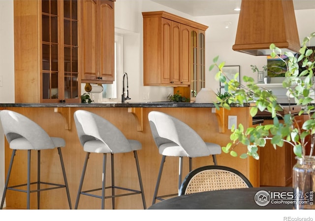 kitchen with a breakfast bar area, sink, and dark stone counters