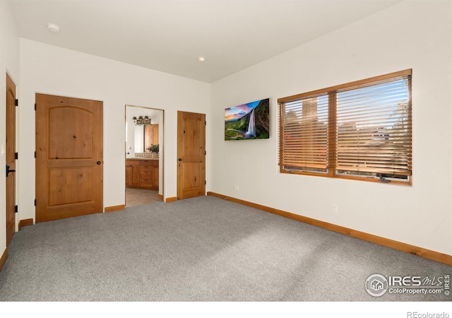 unfurnished bedroom featuring light colored carpet and ensuite bathroom