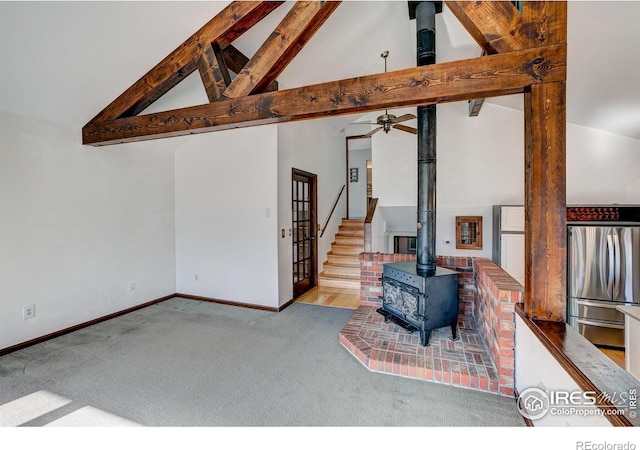 carpeted living room with beam ceiling, high vaulted ceiling, ceiling fan, and a wood stove