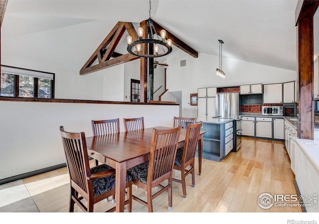 dining space featuring lofted ceiling with beams, light wood-type flooring, and an inviting chandelier