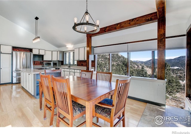 dining room featuring a mountain view, light wood-type flooring, lofted ceiling with beams, and a chandelier