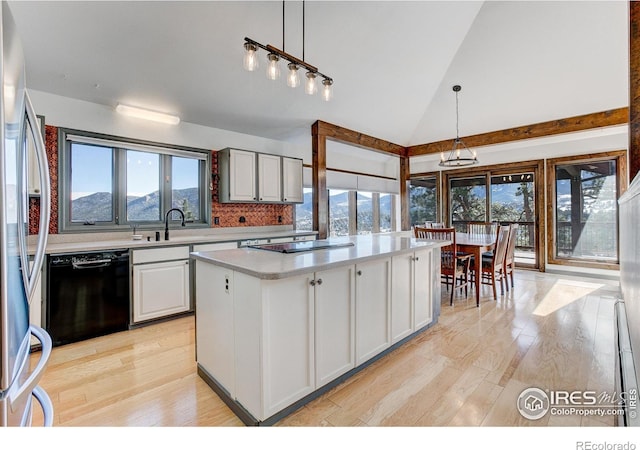 kitchen featuring a mountain view, light wood-type flooring, decorative light fixtures, and black appliances