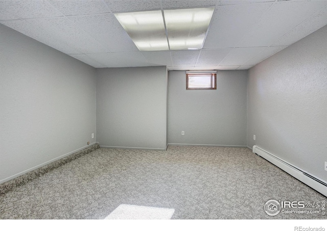 basement with a drop ceiling, carpet, and baseboard heating