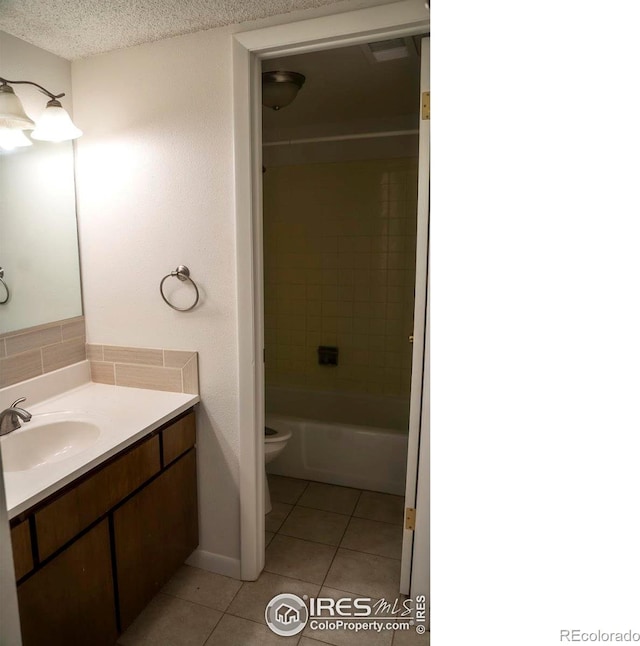 full bathroom featuring vanity, a textured ceiling, tiled shower / bath combo, tile patterned flooring, and toilet