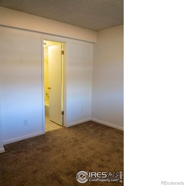 carpeted spare room featuring a textured ceiling