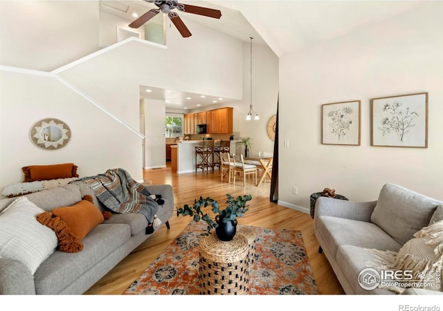 living room with ceiling fan, high vaulted ceiling, and light hardwood / wood-style flooring