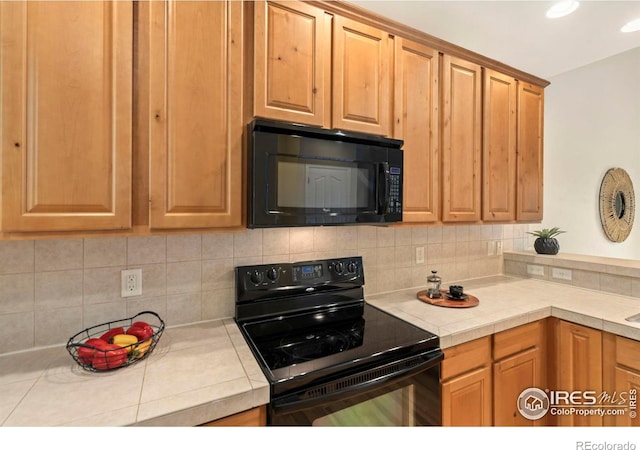 kitchen with tile countertops, tasteful backsplash, and black appliances