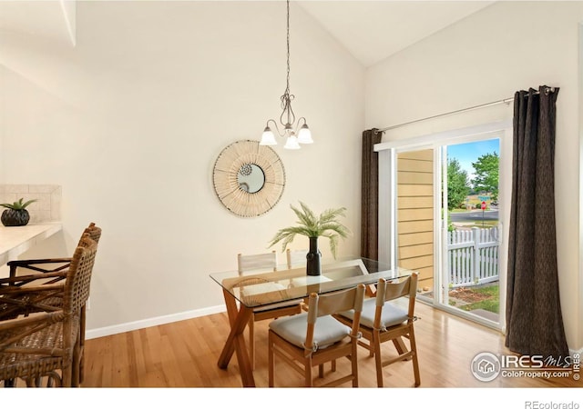 dining space featuring a notable chandelier, light hardwood / wood-style floors, and vaulted ceiling