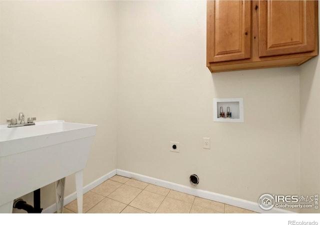 washroom with sink, cabinets, hookup for an electric dryer, hookup for a washing machine, and light tile patterned flooring