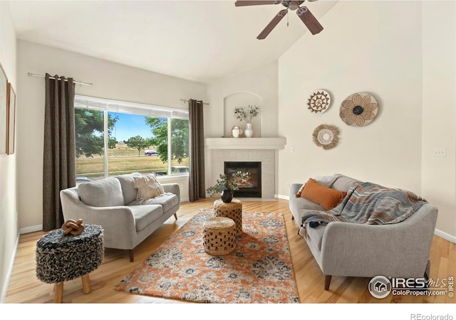 living room with ceiling fan, a fireplace, high vaulted ceiling, and light hardwood / wood-style floors