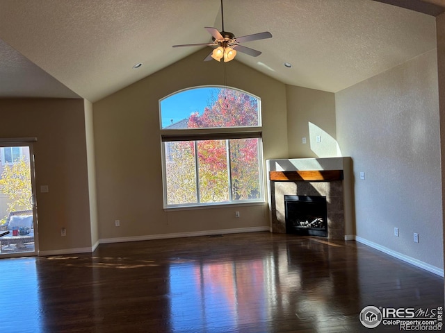 unfurnished living room featuring vaulted ceiling, ceiling fan, a tile fireplace, and dark hardwood / wood-style floors