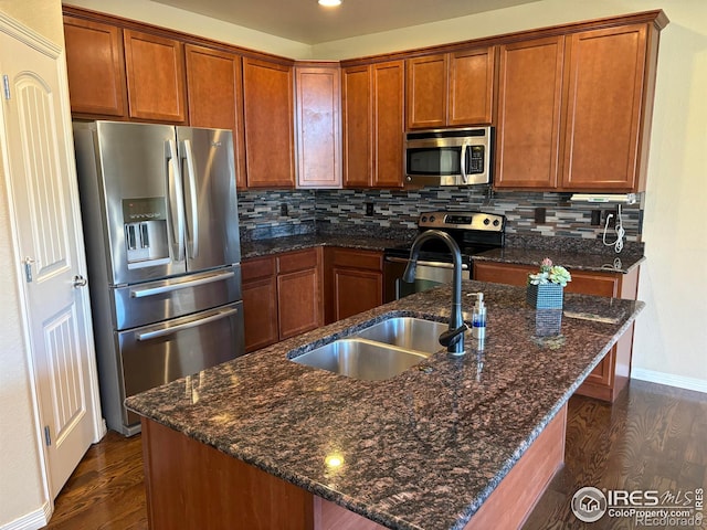 kitchen featuring decorative backsplash, an island with sink, dark wood-type flooring, and appliances with stainless steel finishes