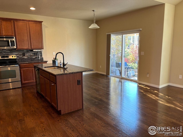 kitchen featuring sink, stainless steel appliances, dark wood-type flooring, dark stone countertops, and an island with sink