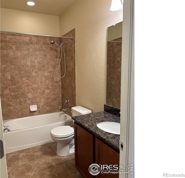 full bathroom featuring vanity, tiled shower / bath combo, toilet, and tile patterned flooring