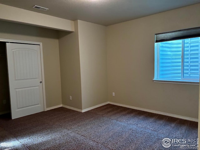 unfurnished bedroom featuring a closet and dark carpet