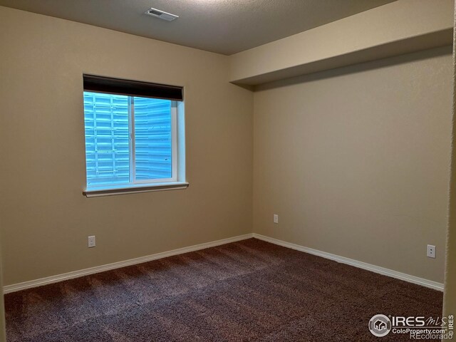 unfurnished room with a textured ceiling and carpet flooring