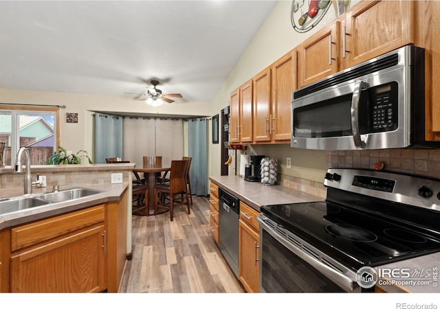 kitchen with stainless steel appliances, ceiling fan, sink, light hardwood / wood-style flooring, and lofted ceiling