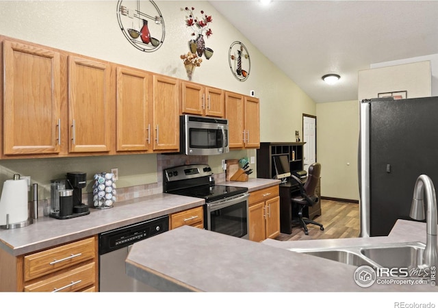 kitchen with sink, light hardwood / wood-style flooring, lofted ceiling, and appliances with stainless steel finishes