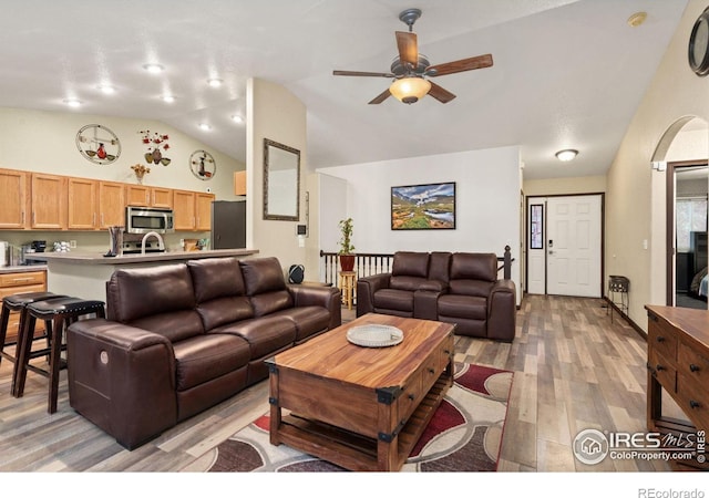 living room featuring lofted ceiling, ceiling fan, and light wood-type flooring