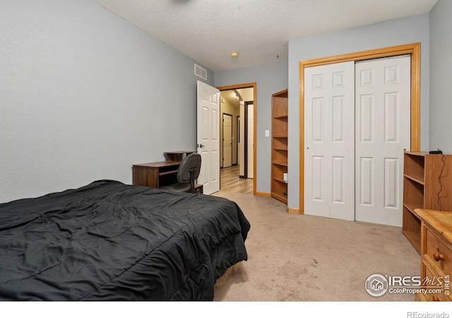 bedroom featuring a textured ceiling, light colored carpet, and a closet