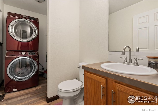 bathroom with vanity, toilet, wood-type flooring, and stacked washer and clothes dryer