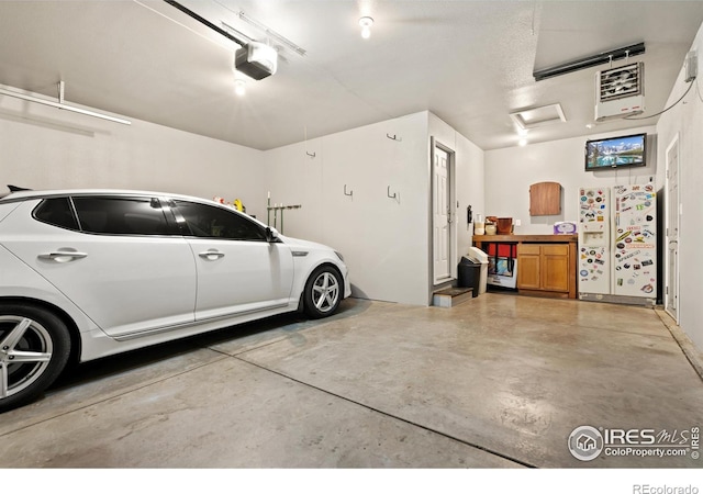 garage with a garage door opener and white refrigerator