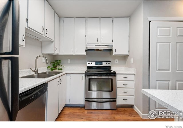 kitchen with white cabinets, appliances with stainless steel finishes, wood-type flooring, and sink