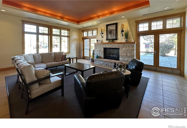 tiled living room with a tray ceiling and a healthy amount of sunlight