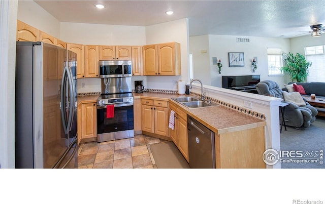 kitchen with light brown cabinetry, kitchen peninsula, sink, and stainless steel appliances