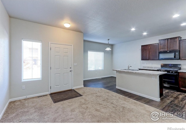 kitchen featuring pendant lighting, a kitchen island with sink, a healthy amount of sunlight, and black appliances